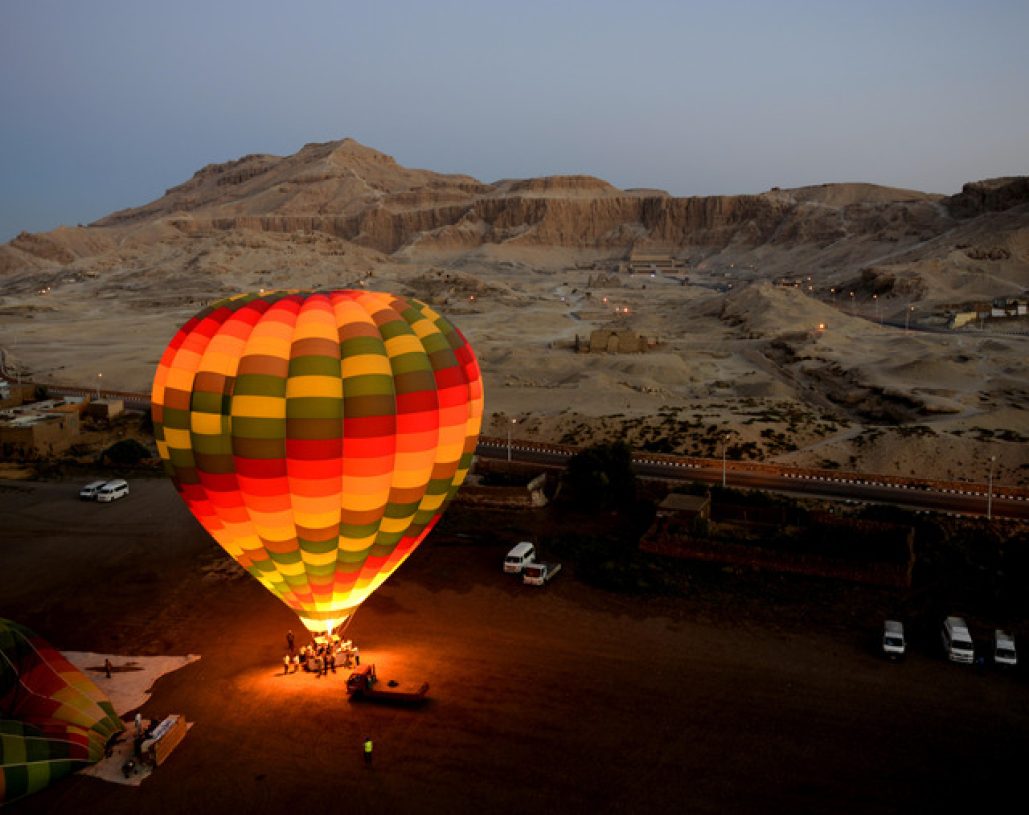 hot air balloon glowing ready for accent at the valley of the kings / temple of hatshepsut in luxor egypt.